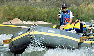 A river rat pauses to flash the peace sign while running Tanner Rapids of the Colorado River, Grand Canyon National Park. #10058. (c) Rob Kleine.  All Rights Reserved